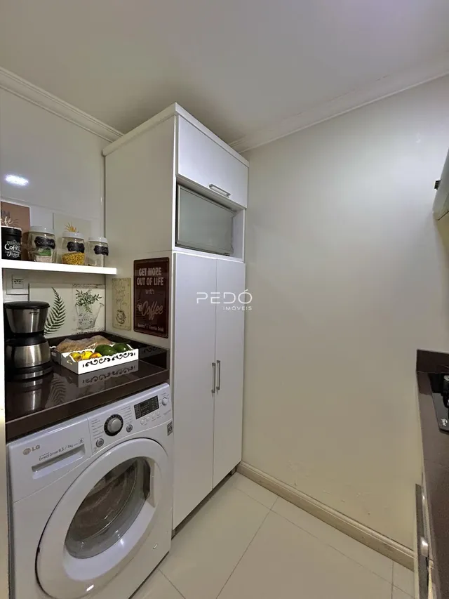 Interior de uma cozinha com armários brancos e máquina de lavar roupa.