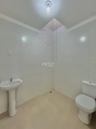 Foto de um banheiro com revestimento cerâmico branco.