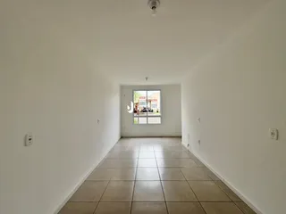 Corredor interno com piso de cerâmica claro.