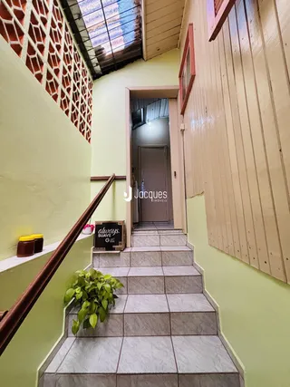 Escadaria interna com paredes verdes e piso de cerâmica.