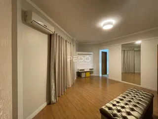 Sala de estar com piso de madeira e cortinas claras.