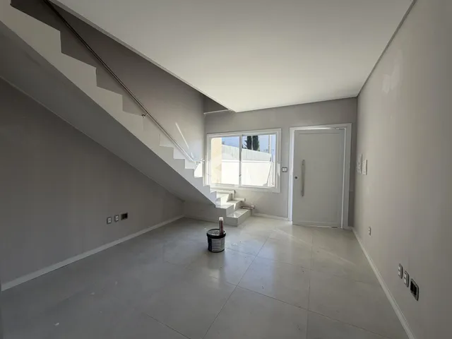 Interior de um espaço com teto inclinado e escadaria em uma residência.