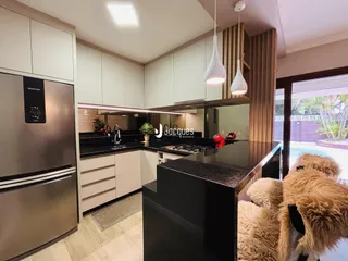 Cozinha moderna com armários brancos e bancadas escuras.