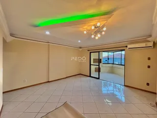 Sala de estar ampla com piso de cerâmica clara e teto decorado.