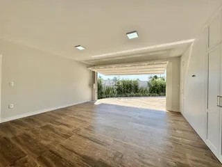 Sala de estar com piso de madeira e acesso a uma área externa.