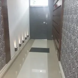 Corredor interno com piso claro e painéis de madeira na parede.