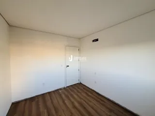 Foto de um cômodo interno com piso de madeira e paredes brancas.