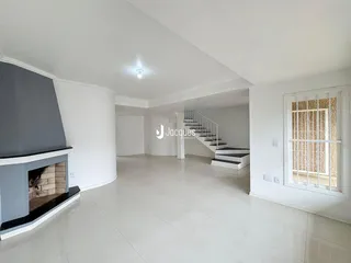 Sala de estar ampla com piso claro e lareira em ambiente residencial.