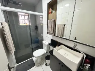 Banheiro com pia e vaso sanitário em azulejos brancos.