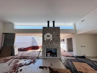 Imagem de uma área interna em construção com paredes brancas e estrutura de pedra.