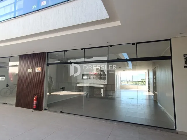 Entrada de um imóvel com portas de vidro e revestimento de madeira.