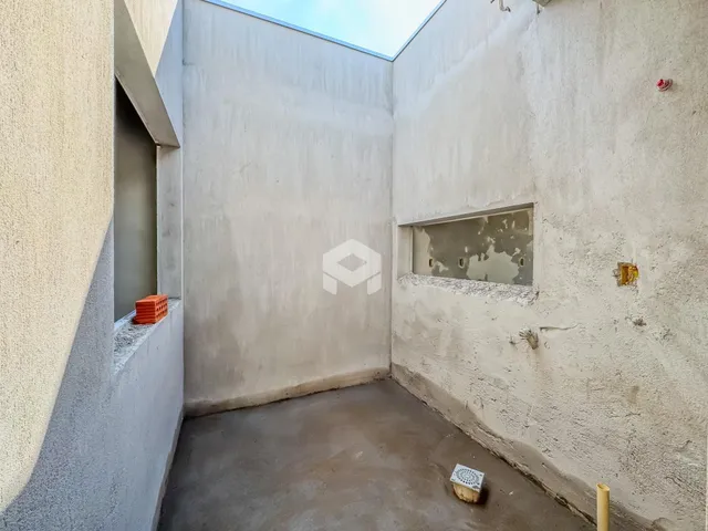Interior de um espaço com paredes brancas e piso de concreto.