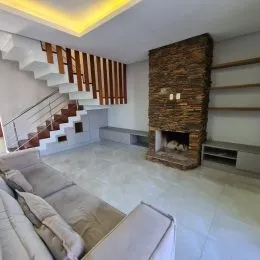 Uma sala de estar com sofá e escadaria visível em um imóvel.