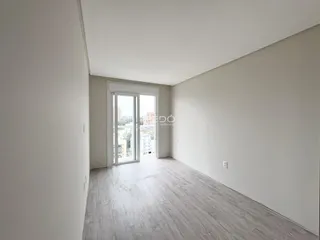 Uma sala com piso de madeira e porta de vidro que dá para o exterior.
