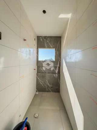 Vista de um corredor interno com paredes brancas e uma parede de destaque em mármore cinza.