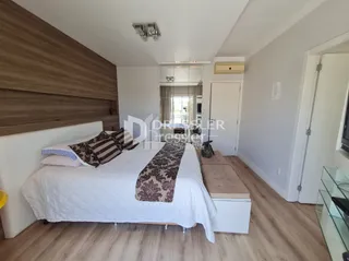 Quarto com cama e piso de madeira clara.
