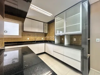 Cozinha moderna com armários brancos e bancadas escuras.