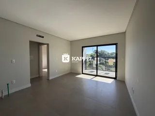Sala de estar ampla com piso de concreto e porta de vidro que dá para a vista externa.