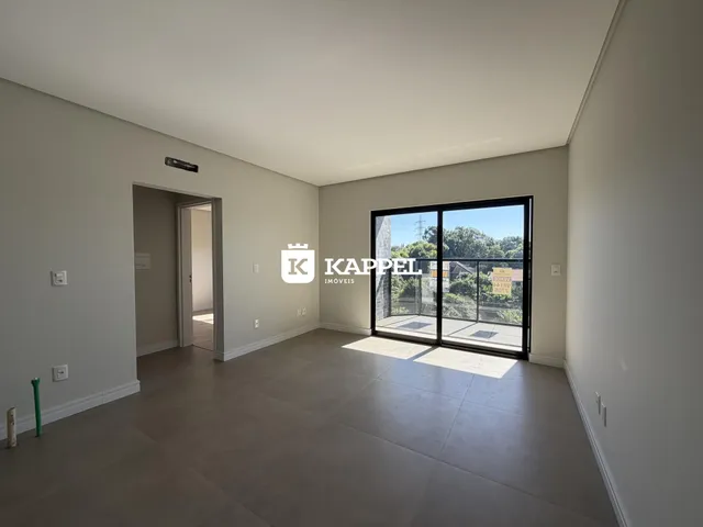 Sala de estar ampla com piso de concreto e porta de vidro que dá para a vista externa.