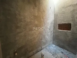 Vista interna de um corredor com paredes de alvenaria ásperas.