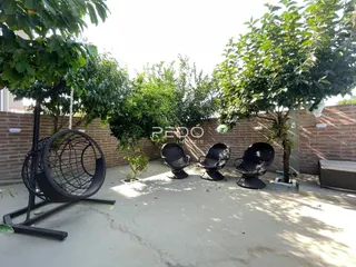 Área externa com vasos de plantas e cadeiras escuras em um pátio.