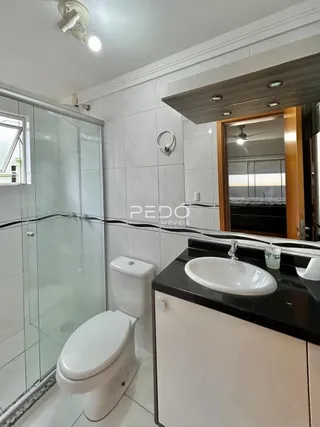 Foto de um banheiro com box de vidro e louças brancas.