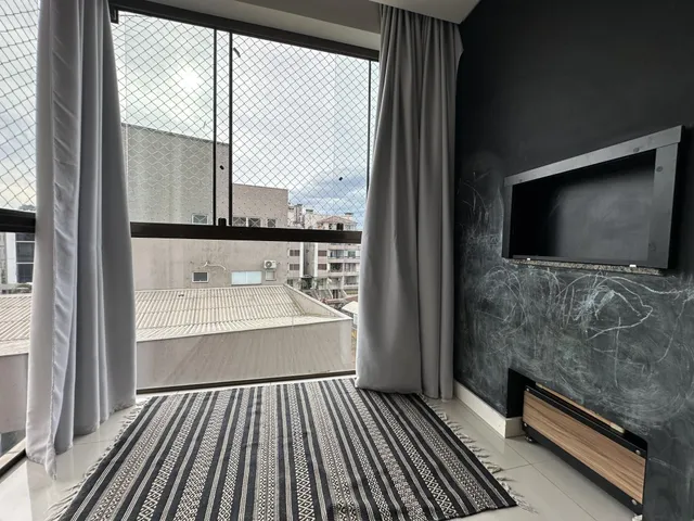 Vista da sala com grandes janelas e cortinas.