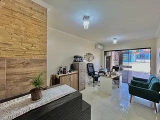 Sala de estar com parede de pedra e porta de vidro abrindo para o exterior.