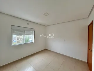 Ambiente interno de uma sala com piso de cerâmica e janela.