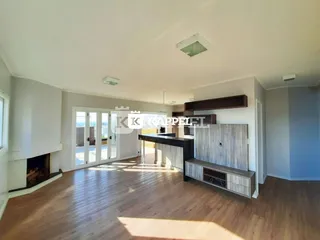 Sala de estar com piso de madeira e acesso a uma área externa com vista.