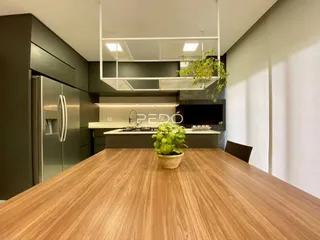 Vista interna de uma cozinha moderna com armários verdes e bancadas brancas.