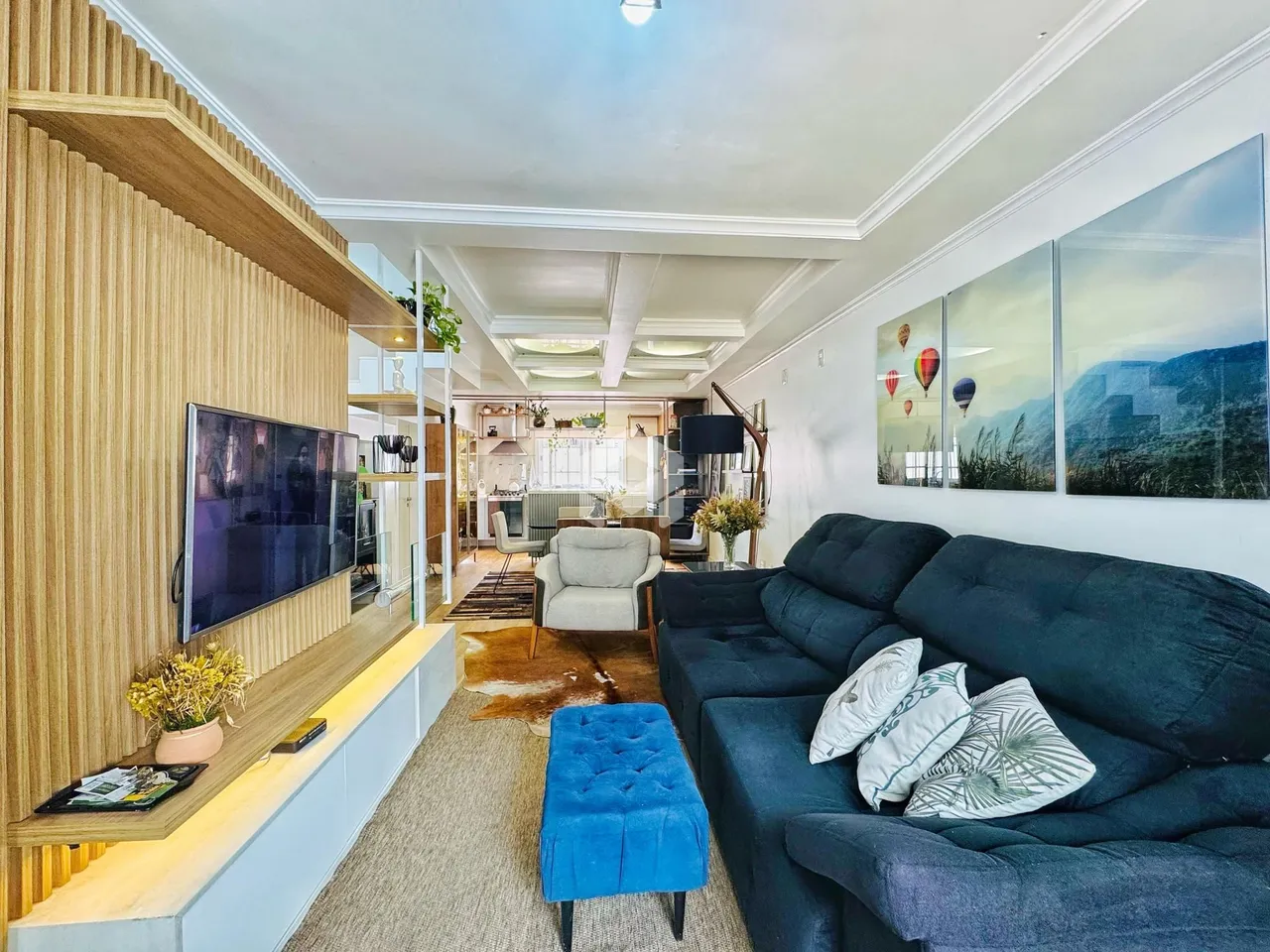 Sala de estar moderna com sofá e televisão em um ambiente claro.