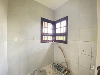 Parede interna com revestimento de azulejos brancos e duas janelas de madeira.