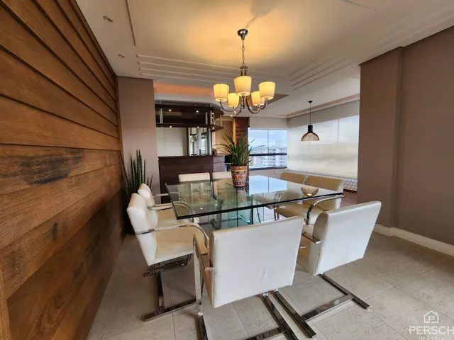 Uma sala de jantar com mesa de vidro e cadeiras brancas é visível no interior da propriedade.