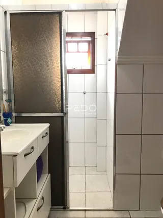 Hall com paredes de azulejo branco e um gabinete de banheiro.