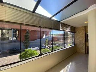 Vista interna de uma sala com grandes janelas que dão para a rua.