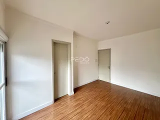 Interior de uma sala com piso de madeira e paredes brancas.