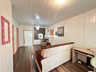 Sala de estar com piso de madeira e sofá marrom.