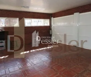 Interior de uma sala com piso de cerâmica avermelhada e paredes de tijolo.