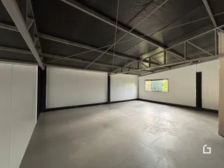 Vista interna de um espaço amplo com estrutura de vigas exposta.
