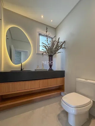 Banheiro moderno com bancada escura e piso claro.