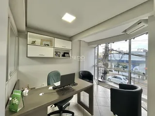 Ambiente interno de um escritório com estantes e uma grande janela.