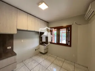 Ambiente interno com piso de cerâmica e armários de madeira clara.
