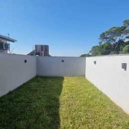 Vista de um jardim gramado ao lado de um muro branco.