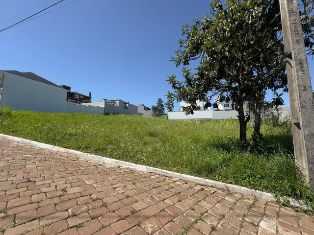 Vista externa de uma propriedade com gramado e residências ao fundo sob um céu azul.