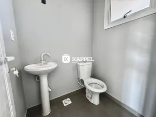 Foto interna de um banheiro mostrando uma pia e um vaso sanitário brancos.