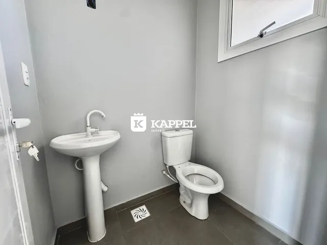 Foto interna de um banheiro mostrando uma pia e um vaso sanitário brancos.