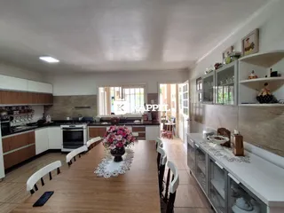Sala de jantar com mesa de madeira e cozinha moderna em um imóvel.