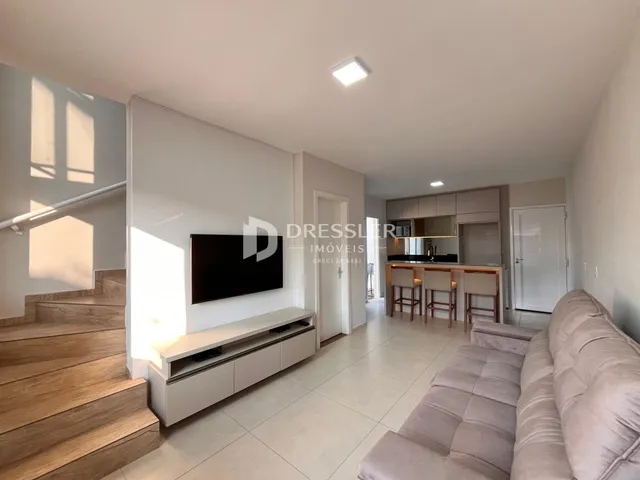 Sala de estar com sofá e escadaria em um imóvel no Brasil.