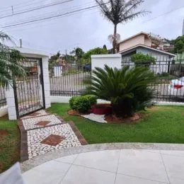 Foto de uma área externa com gramado e vegetação.